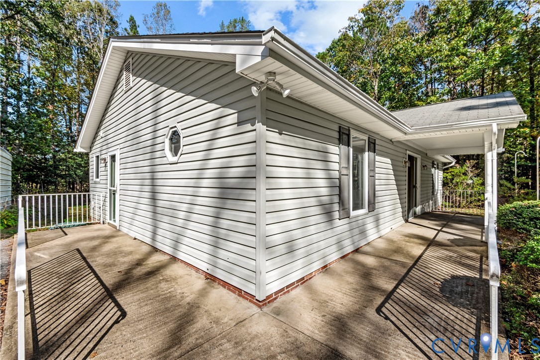 Exterior featuring light gray horizontal siding, a wrap-around concrete porch, white metal railings, and a decorative octagonal window
