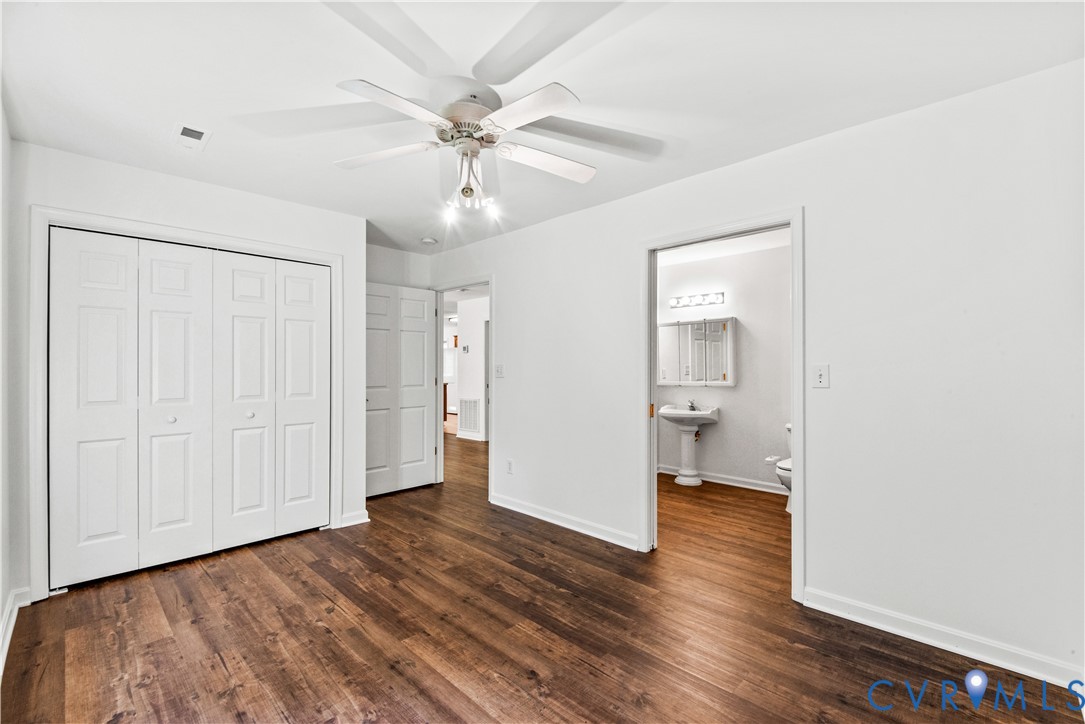 Room featuring wood-finish flooring, a white ceiling fan with integrated lighting, and white six-panel closet doors