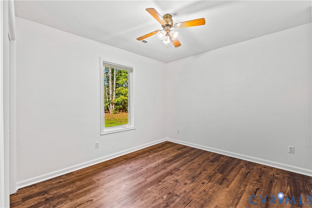 Room featuring wood-finish flooring, a neutral color palette, a single-pane window, and a ceiling fan with integrated lighting
