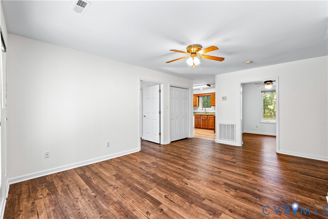 Interior space featuring wood-finish flooring, white walls, and a ceiling-mounted light fixture with an integrated fan