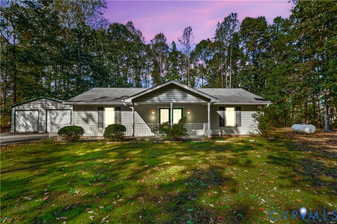 Single-story residence featuring horizontal lap siding, an expansive covered front porch with white railing, and a detached two-car garage