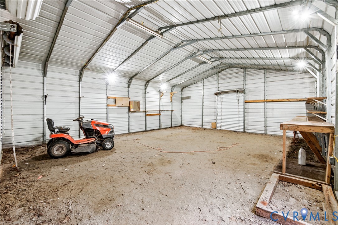 Enclosed metal workshop featuring corrugated wall and ceiling panels, integrated ceiling-mounted lighting, and built-in timber shelving