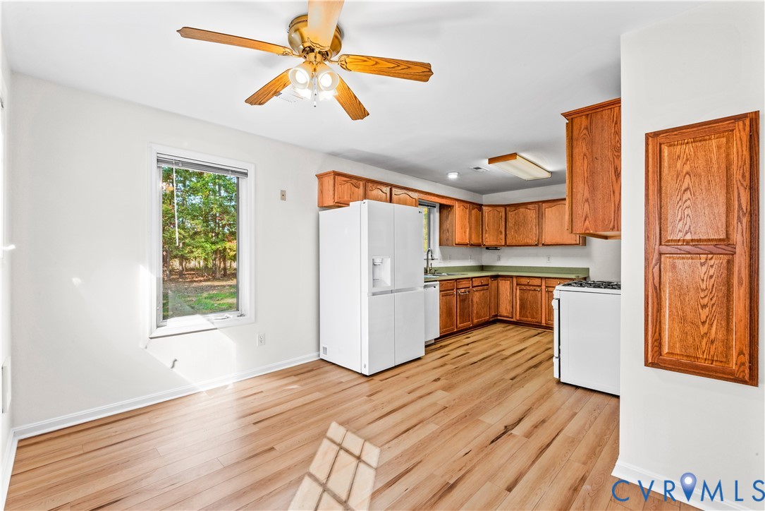 Kitchen featuring wood-finish flooring, oak cabinetry, a built-in recessed cabinet, and a ceiling fan with integrated lighting