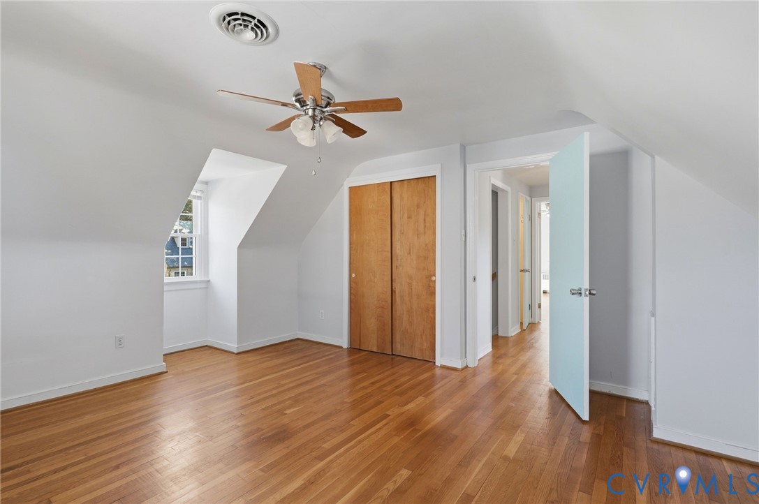 Room featuring wood-finish flooring, a dormer window, and a ceiling fan with integrated light fixture