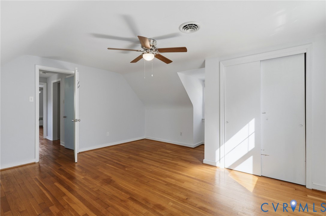 Hardwood flooring, ceiling fan with light fixture, and dual-panel sliding closet doors
