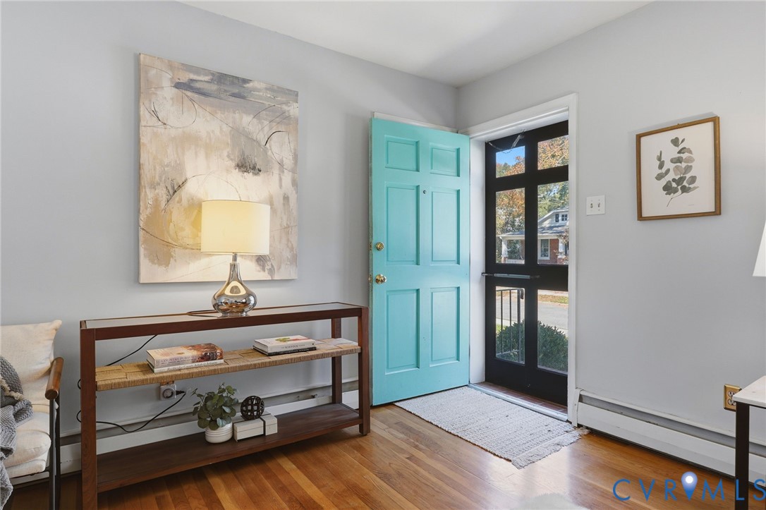 Entryway featuring light-toned interior walls, natural wood-finish flooring, and a multi-panel door with integrated glass panes