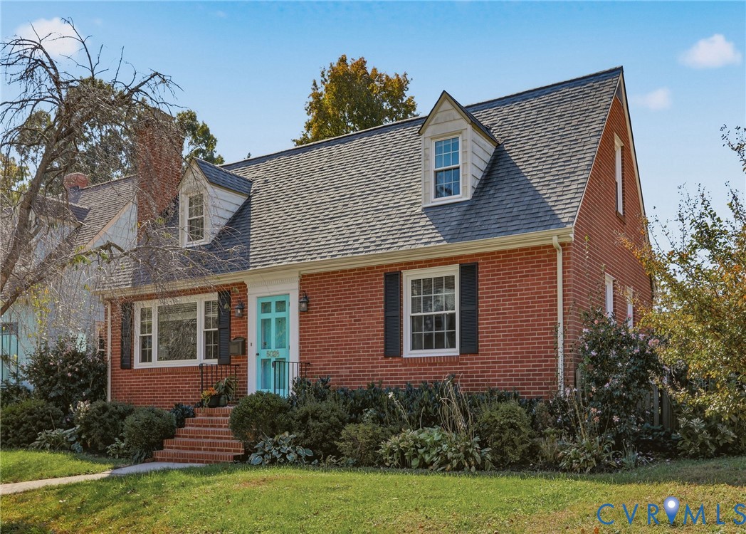 Traditional brick exterior featuring dual gabled dormers, a gable roof, and decorative shutters
