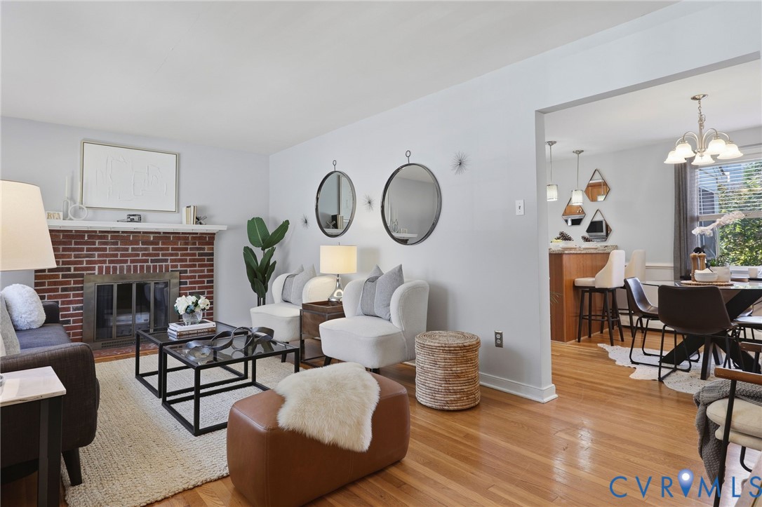 Living area featuring a red brick fireplace with a wood mantel, wood-finish flooring, and a multi-pendant dining light fixture