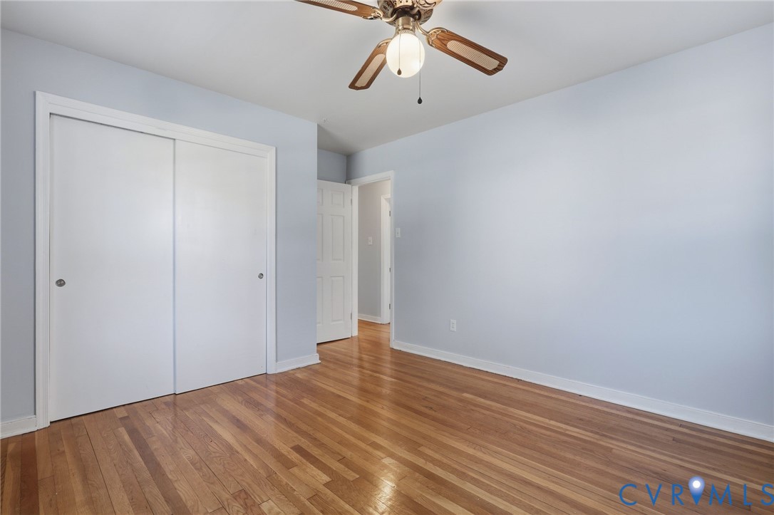 Room featuring wood-finish flooring, sliding-door closet, and ceiling fan with integrated light fixture