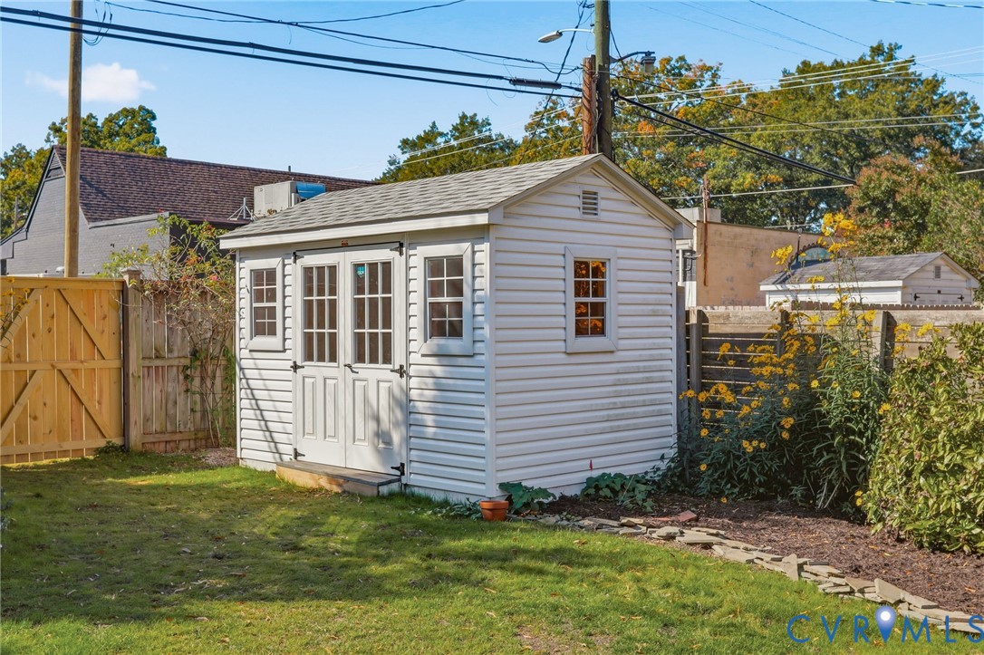 Detached storage shed featuring vinyl siding, shingled roof, double-door entry with glass panes, and side windows