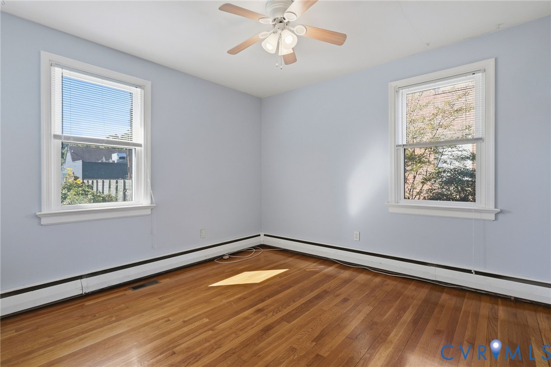 Interior space featuring wood-finish flooring, two double-hung windows, and a ceiling-mounted light fixture with a fan