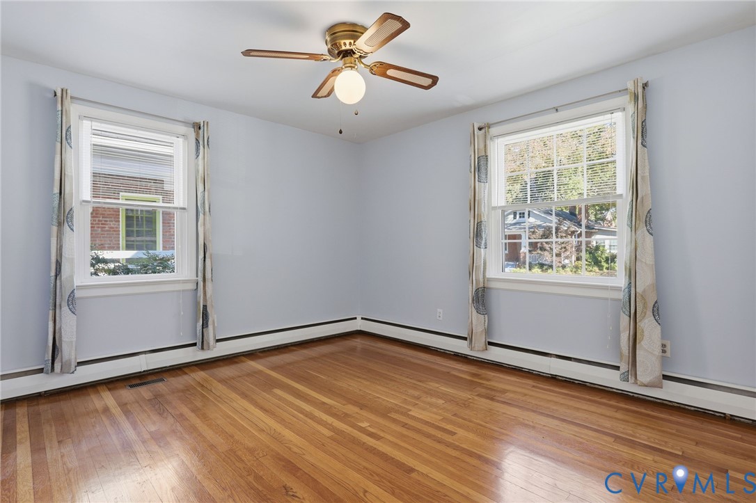 Hardwood flooring, dual multi-pane windows, and a central ceiling fan with integrated lighting