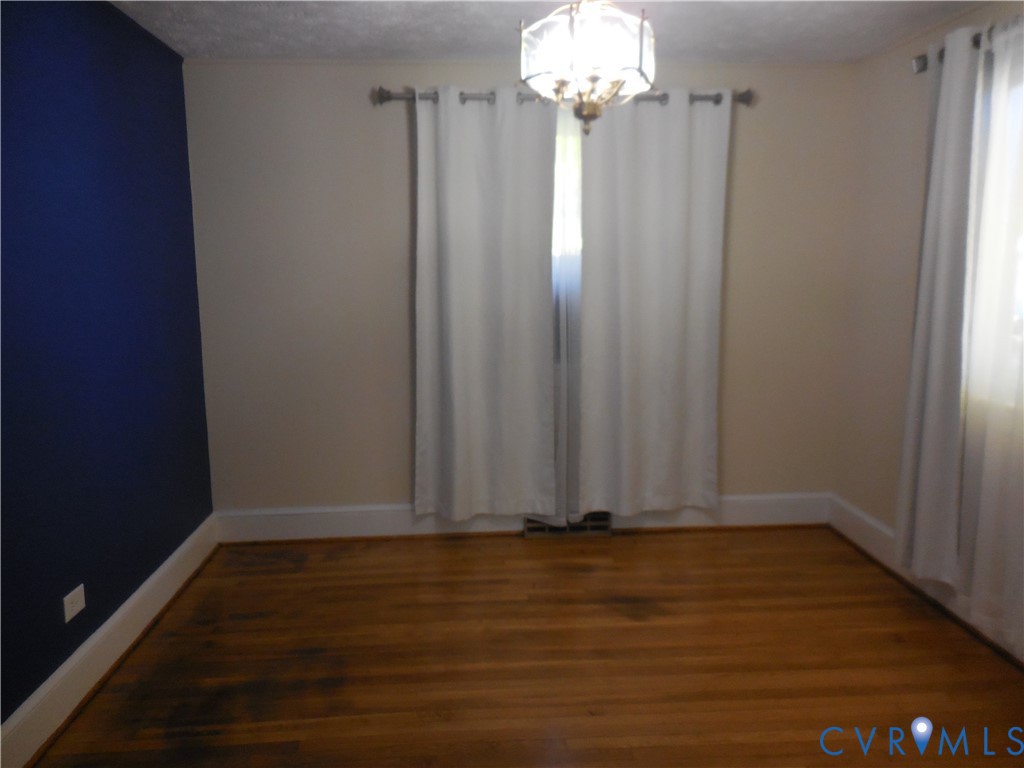 Hardwood flooring, decorative hanging light fixture, and an accent wall