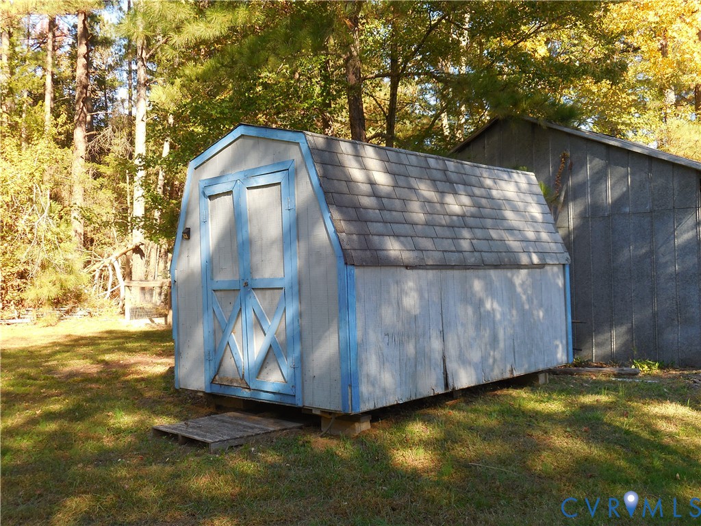 Barn-style storage structure with dual swinging doors, shingled roofing, and wood-panel siding
