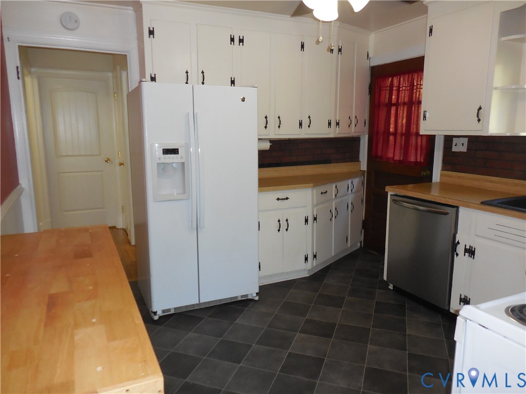 Kitchen featuring white cabinetry with dark iron-finish hardware, solid-surface countertops, a brick backsplash, and checkerboard-patterned floor tile
