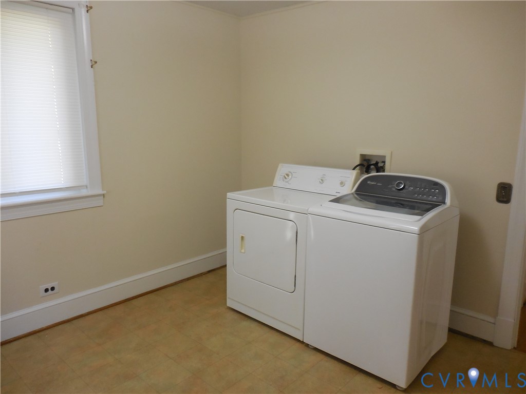 Dedicated utility area featuring a window with integrated blinds and resilient tile flooring
