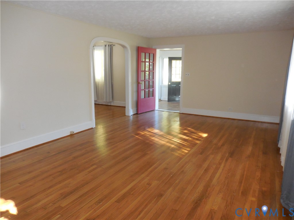 Interior space featuring wood-finish flooring, an arched entryway, and a multi-pane glass door