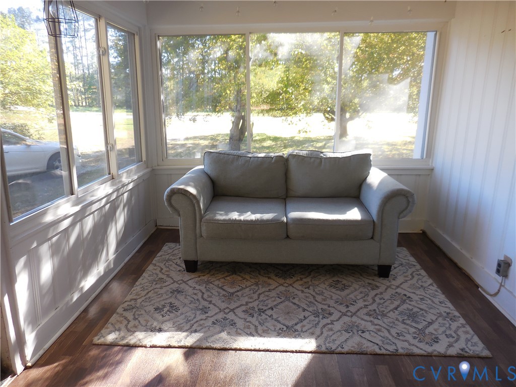 Enclosed sunroom featuring expansive windows, wood-finish flooring, and vertical wall paneling