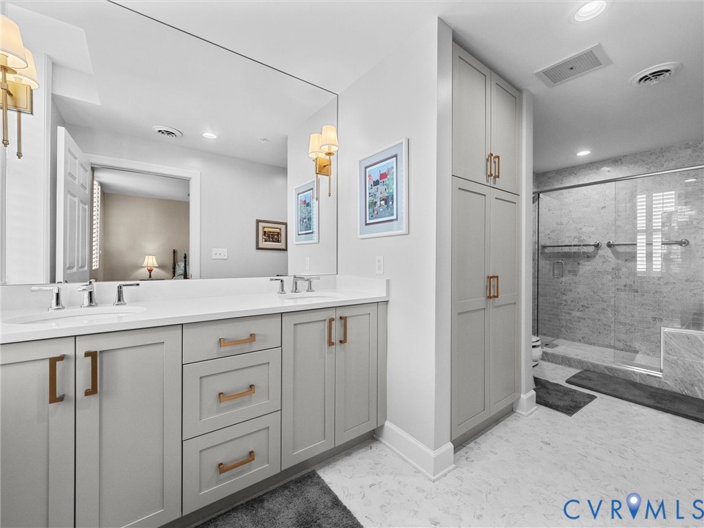 Primary bath with double vanity, built-in linen closet and large walk-in marble shower.