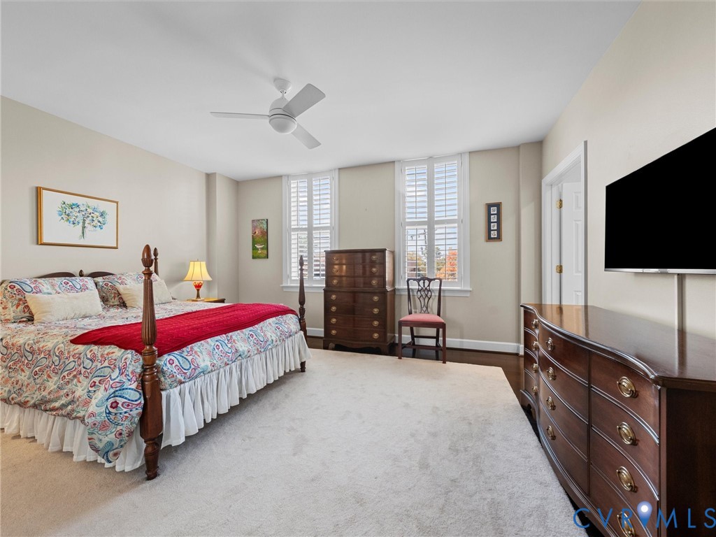 Spacious primary bedroom with multiple windows with plantation shutters.