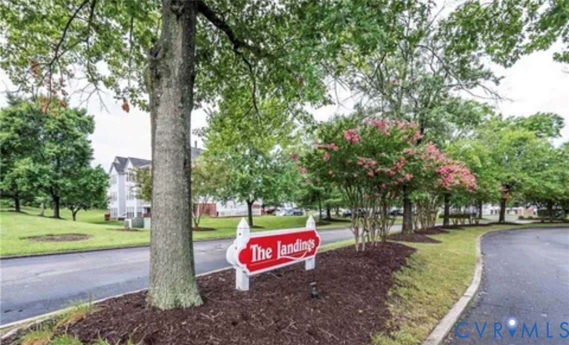 Landscaped grounds featuring mature trees, flowering shrubs, dark mulch beds, and paved roadways Landscaped grounds featuring mature trees, flowering shrubs, dark mulch beds, and paved roadways
