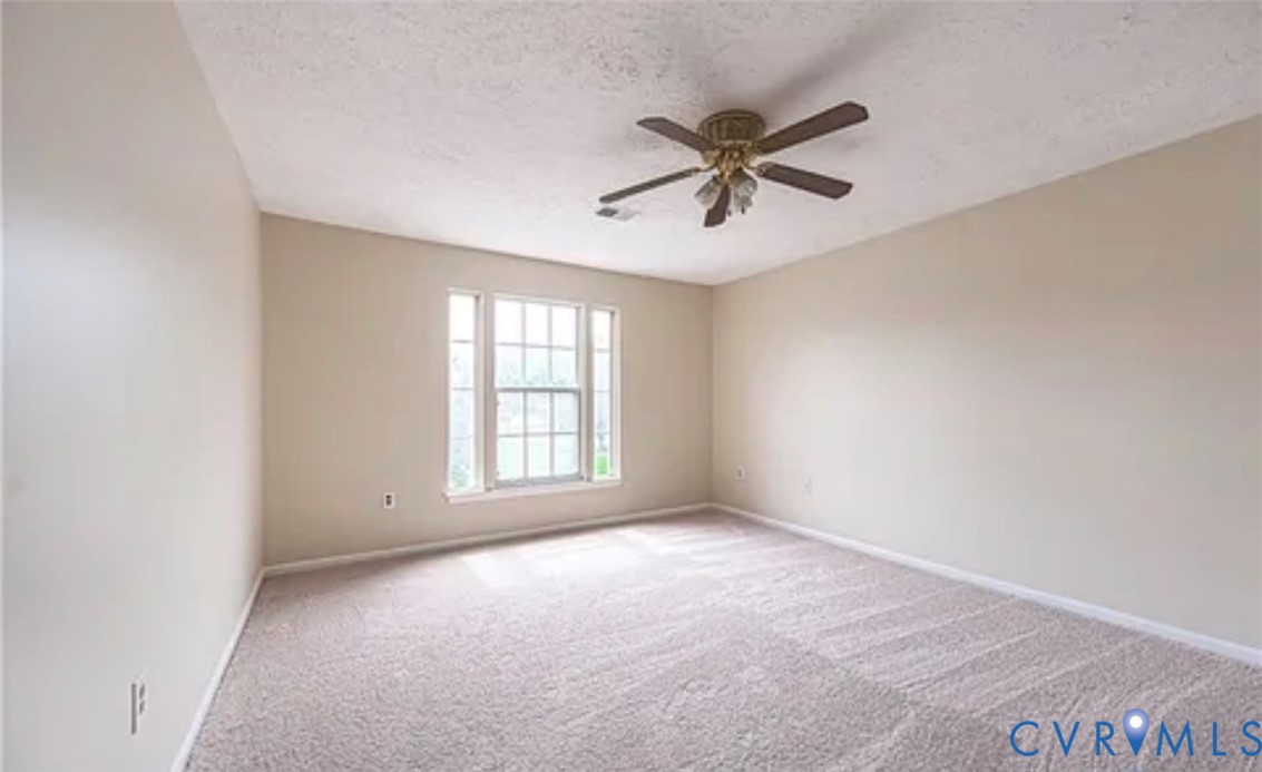 Neutral-toned room featuring wall-to-wall carpeting, a multi-pane window, and a ceiling-mounted fan with integrated lighting