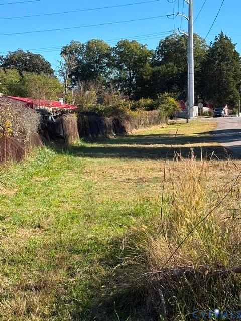 Cleared parcel featuring native grasses, mature perimeter trees, and wire mesh fencing