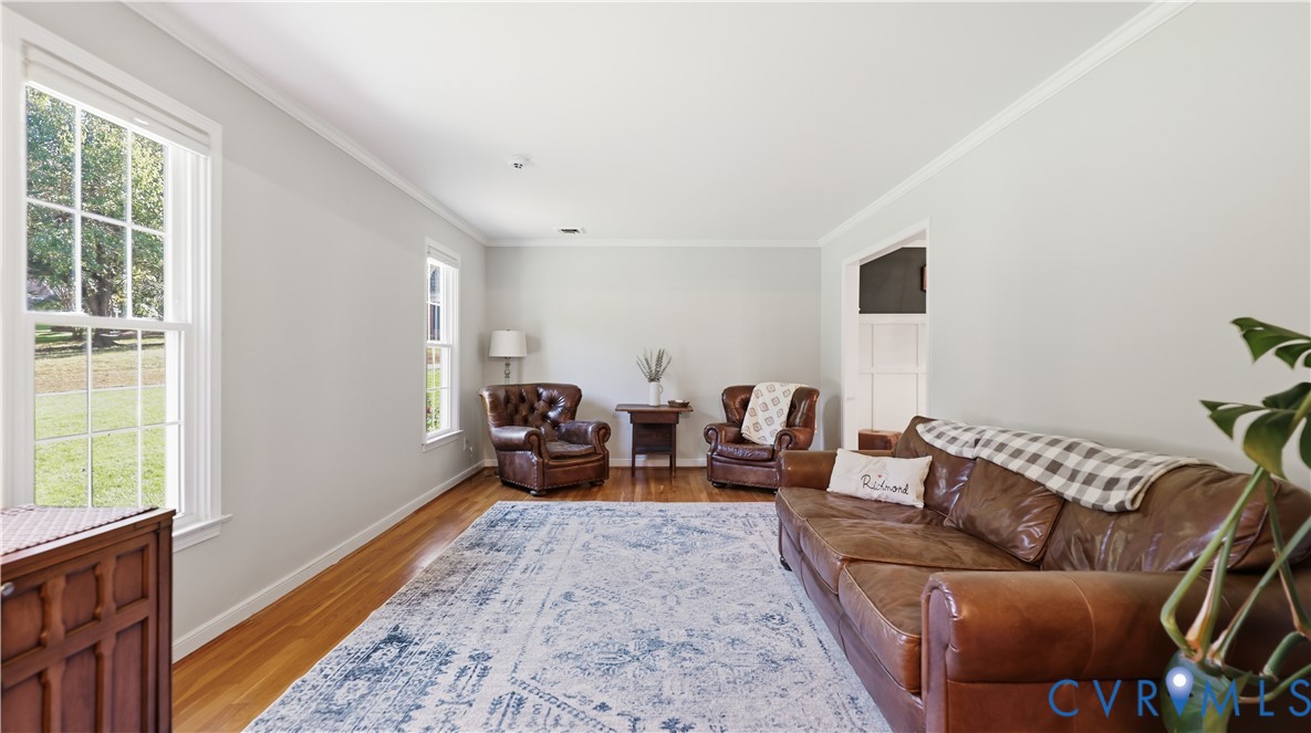 Living area featuring light-toned neutral walls, multiple multi-pane windows, and polished wood-finish flooring