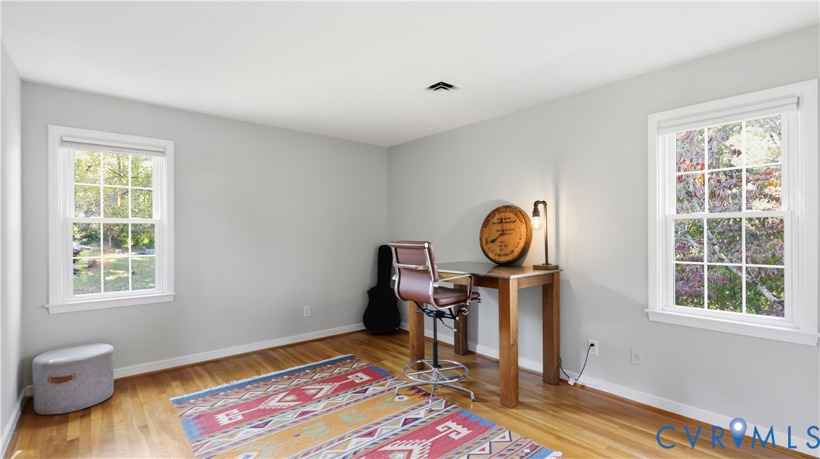 Room featuring wood-finish flooring, neutral wall paint, and dual multi-pane windows
