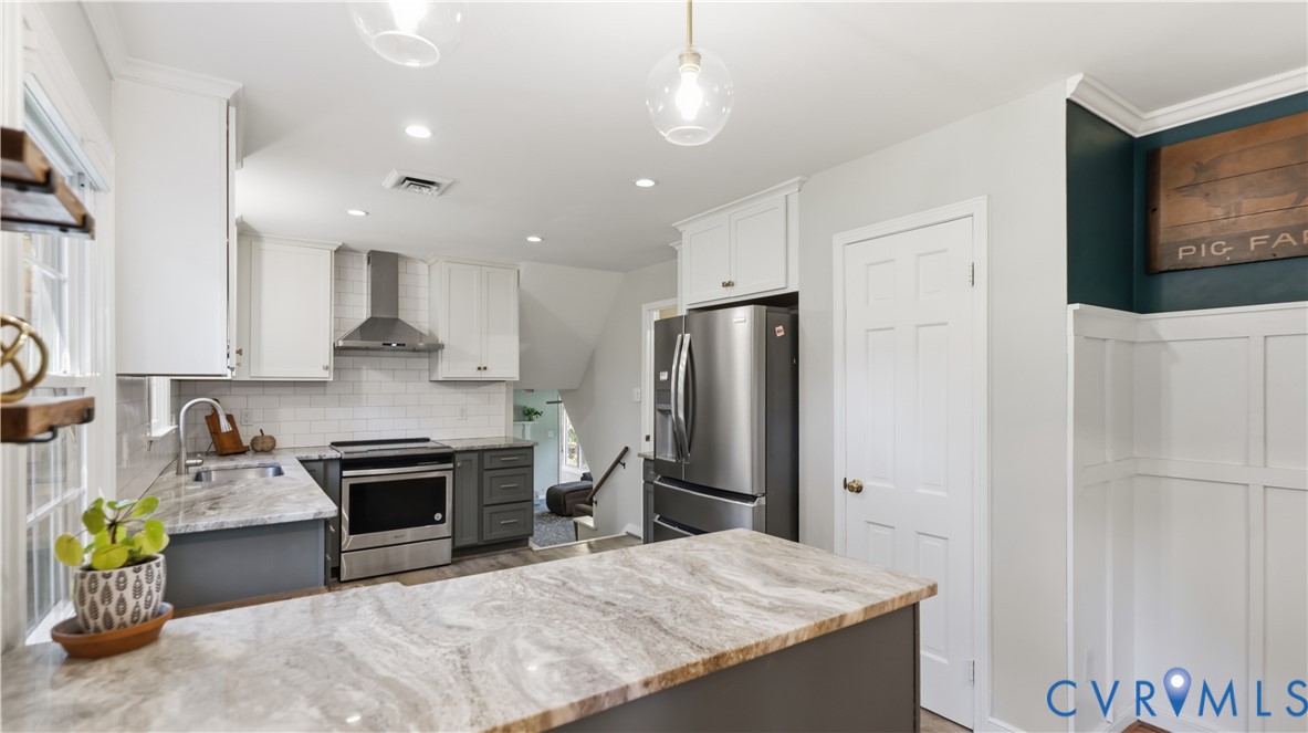 Kitchen featuring white shaker-style upper cabinets, stone-finish countertops, stainless steel appliances, subway tile backsplash, and beadboard wall paneling