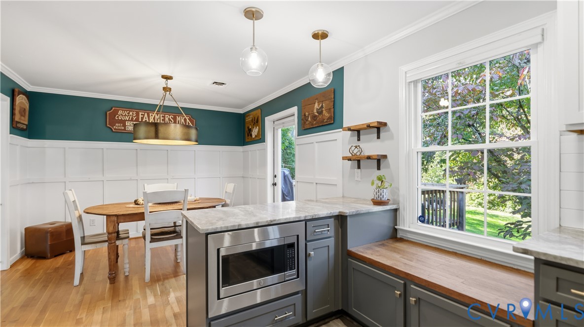 Kitchen featuring custom cabinetry with stone countertops, integrated microwave, built-in wooden bench seating, and wall-mounted shelving