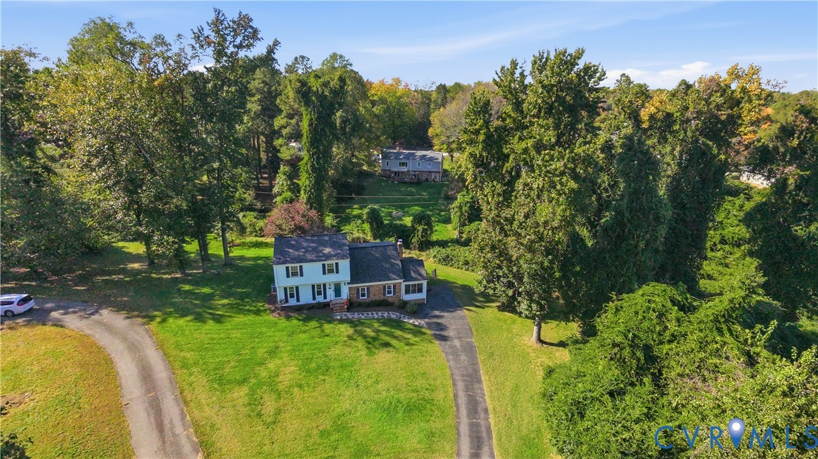 Two-story residence featuring light-colored siding, a mixed brick facade, a shingled roof, a paved driveway, and established trees on a spacious lot