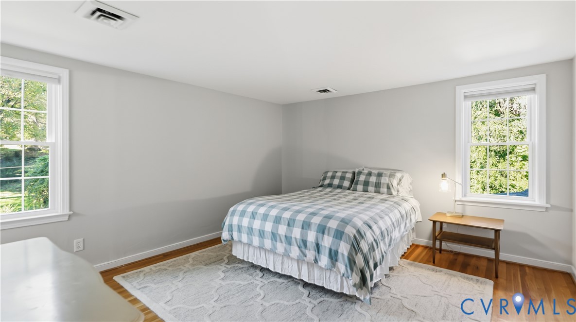 Neutral-toned interior room featuring wood-finish flooring and dual double-hung windows with exterior grid detailing