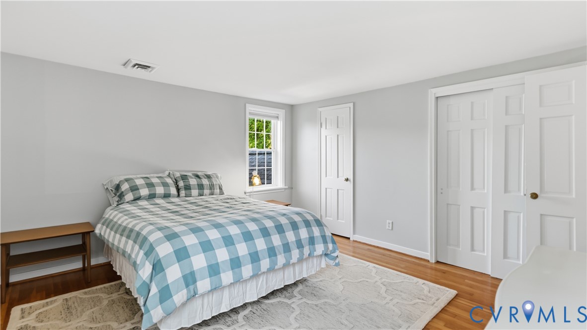 Room featuring neutral wall paint, wood-finish flooring, a double-panel closet, a six-panel door, and a single-hung window