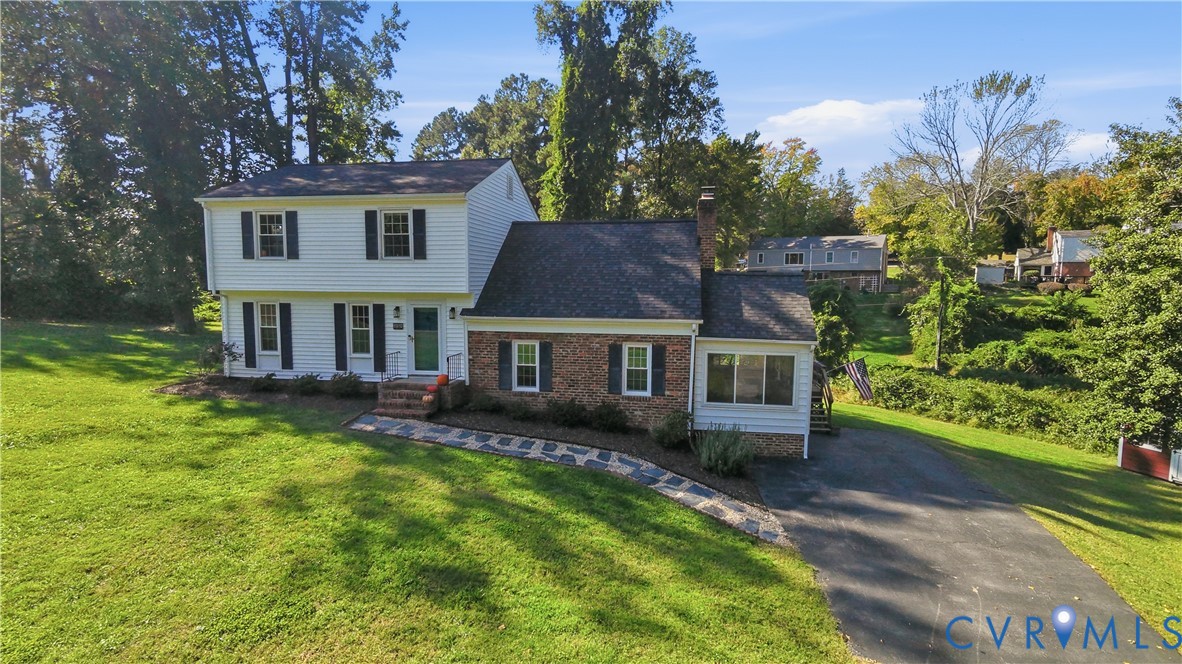 Two-story residence featuring white horizontal siding, a red brick veneer lower level, asphalt shingle roof, flagstone walkway, and an asphalt driveway