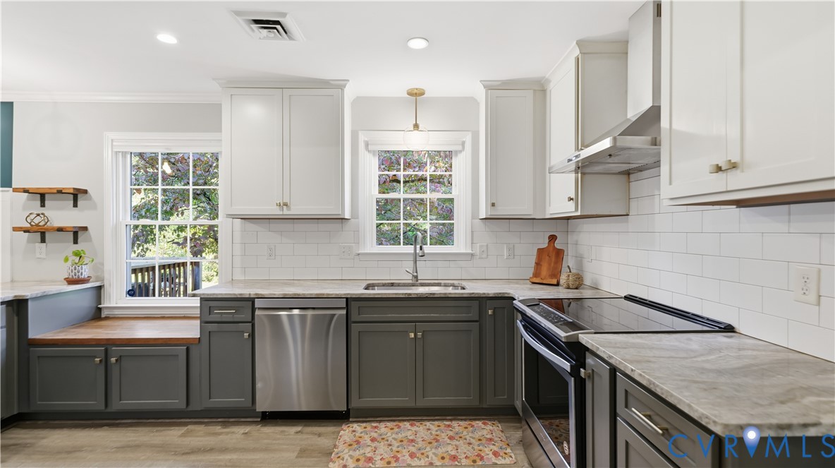 Kitchen featuring two-tone cabinetry, stone-finish countertops, white subway tile backsplash, stainless steel appliances, and integrated wood-finish window seat