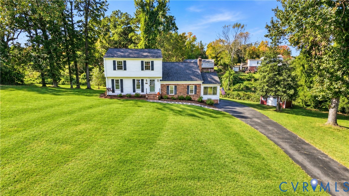 Two-story exterior featuring a brick and white siding facade, asphalt shingle roof, dark window shutters, expansive green lawn, and paved driveway Two-story exterior featuring a brick and white siding facade, asphalt shingle roof, dark window shutters, expansive green lawn, and paved driveway