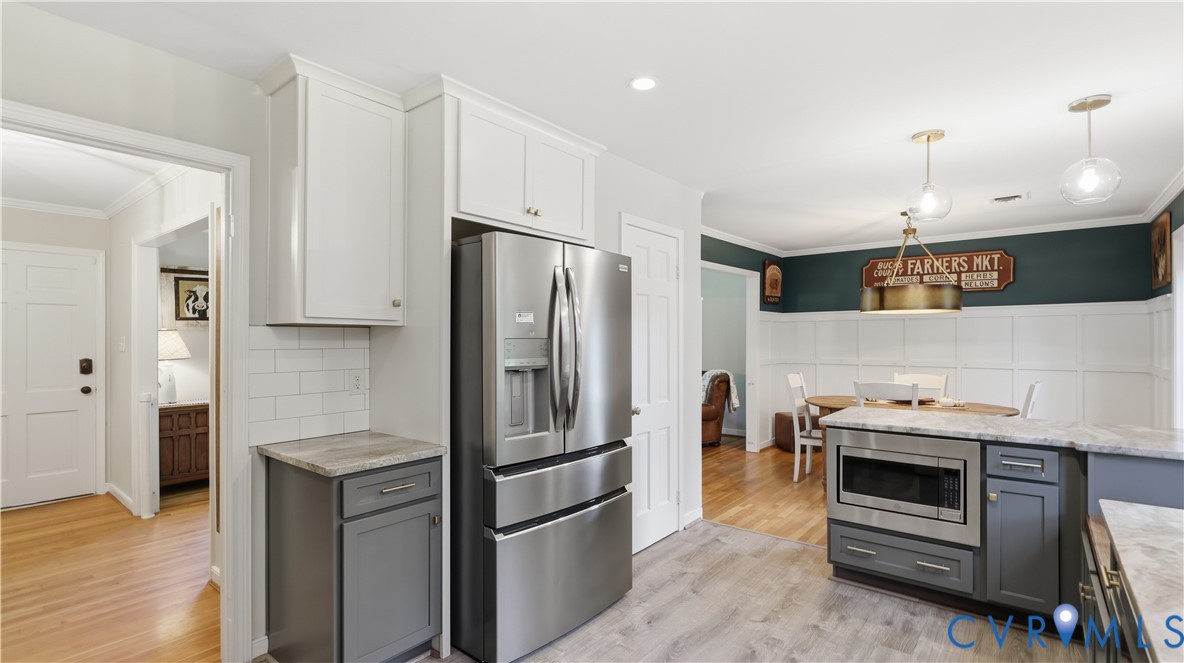 Kitchen featuring white shaker-style cabinetry, grey lower cabinets, stainless steel appliances, white subway tile backsplash, and wood-finish flooring