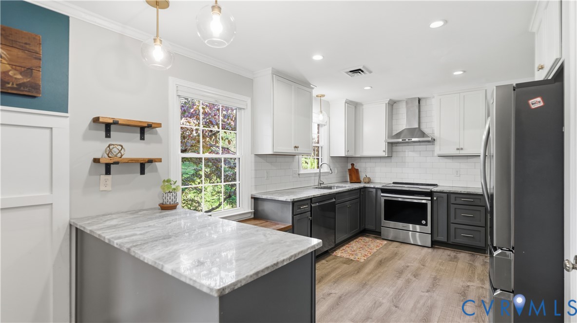 Kitchen featuring dual-tone cabinetry, stone-finish countertops, stainless steel appliances, white subway tile backsplash, and wood-finish flooring