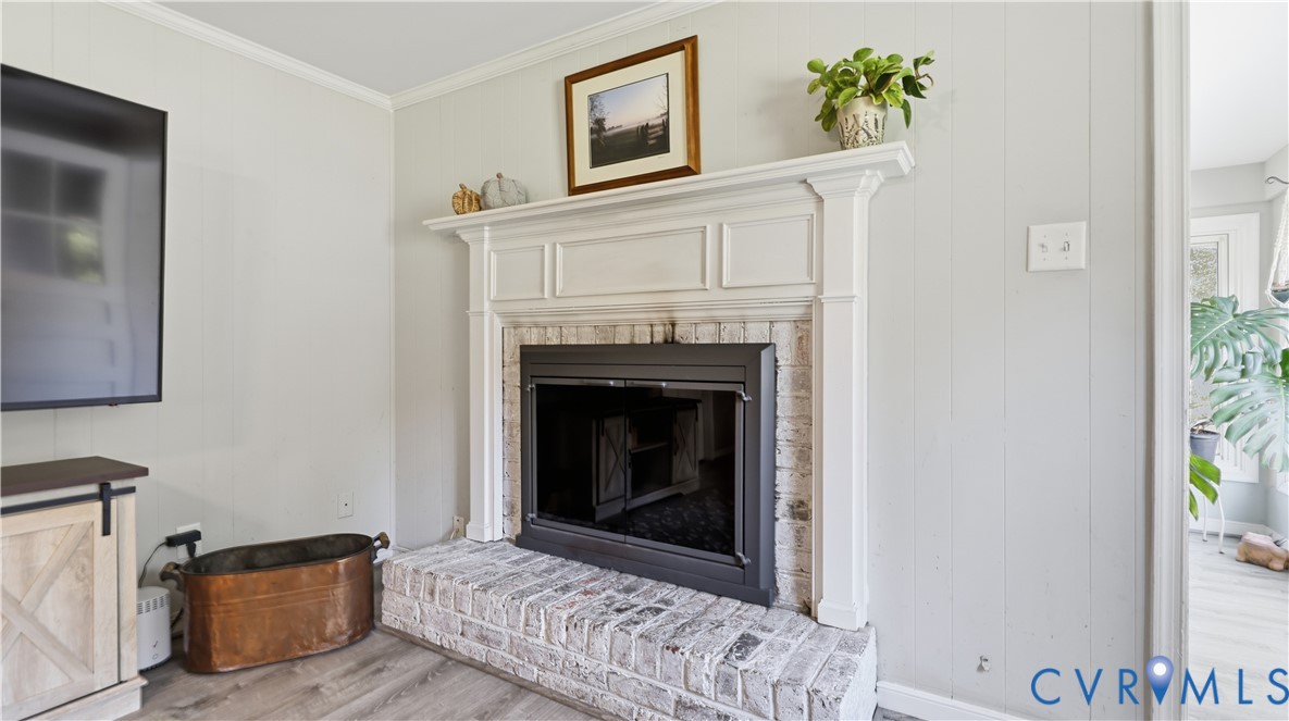 Fireplace featuring a white-painted brick hearth, white custom mantel, wood-finish flooring, and vertical shiplap wall paneling