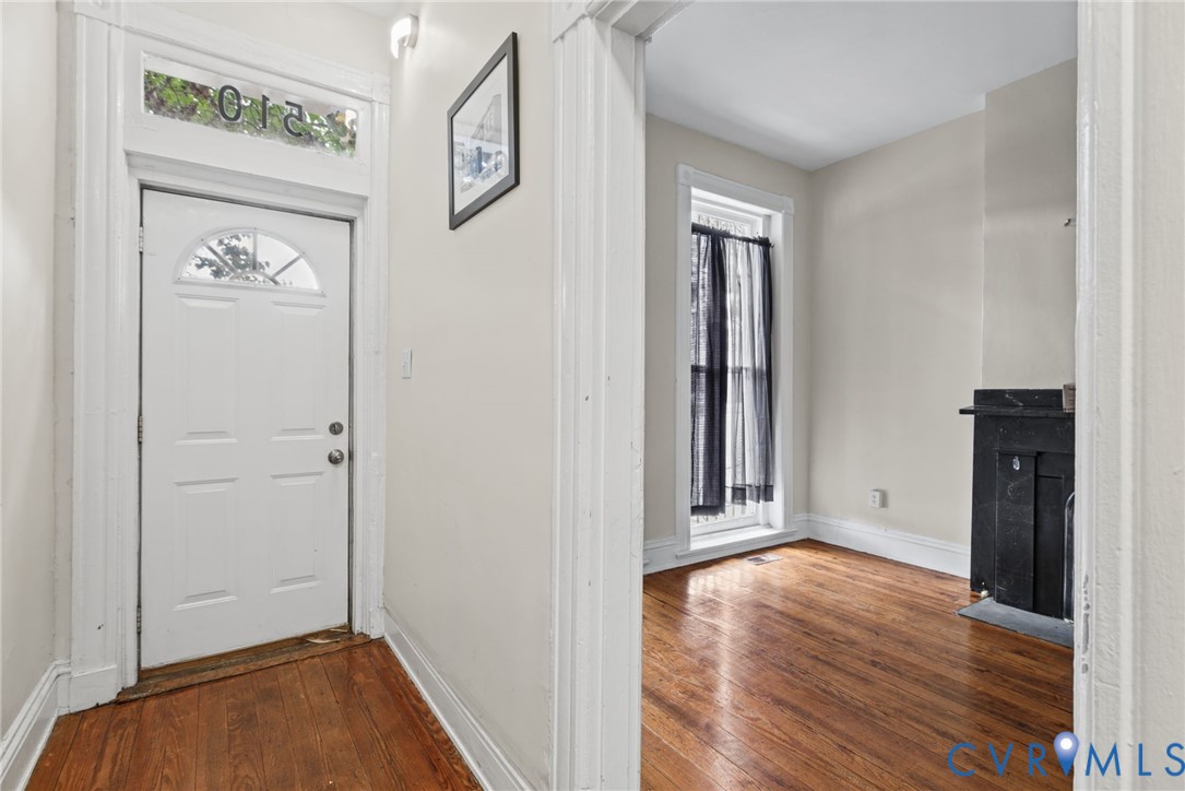Entryway featuring a white door with a glass transom, wood-finish flooring, and a decorative fireplace surround
