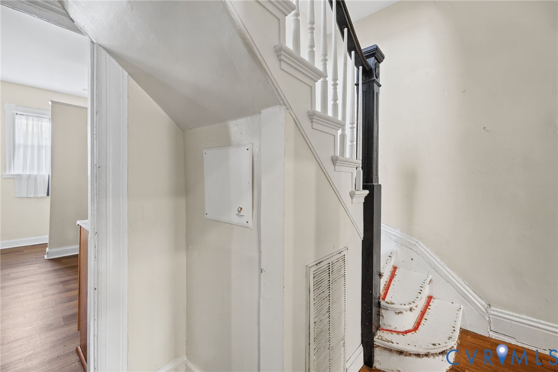 Staircase featuring white balusters, a dark-toned square newel post, and wood-finish flooring