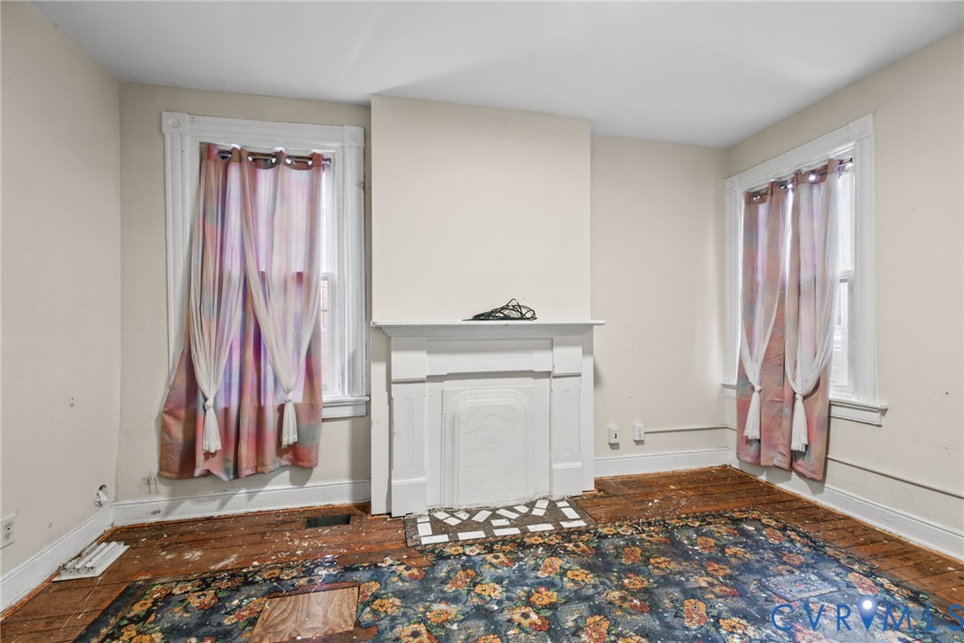 Bedroom 2 - Room featuring original wood flooring, a central decorative fireplace with a mantel, and two windows with molded trim