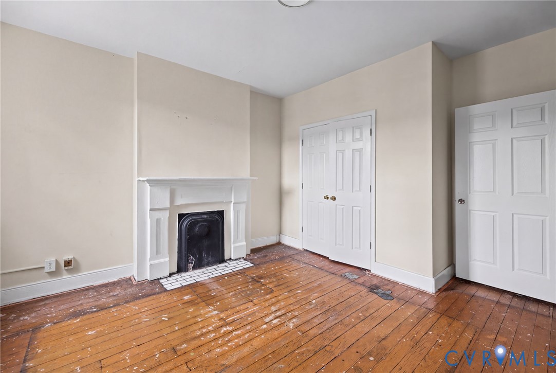 Bedroom 1 - Hardwood flooring, wood-burning fireplace with a mantel, and paneled closet doors