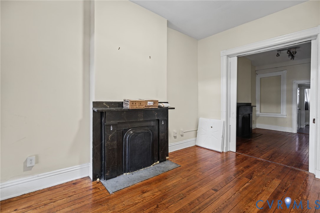 Dark stone fireplace surround with a matching hearth, wood-finish flooring, and high-profile architectural door casing