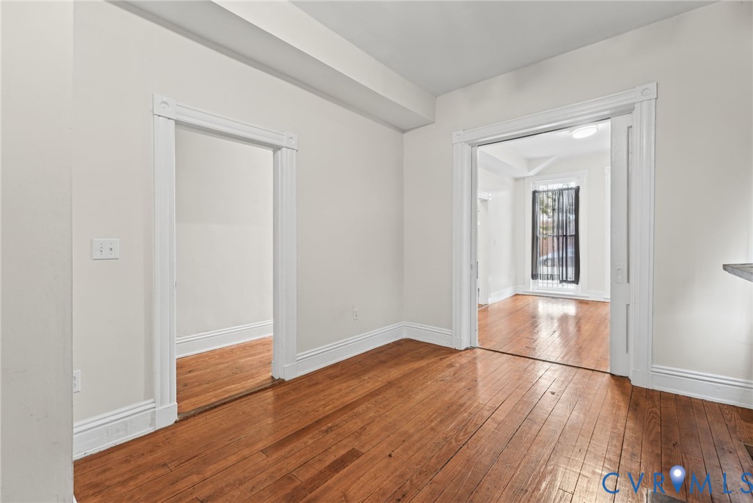 Interior space featuring polished wood-finish flooring, high-profile white door casing, and sliding pocket doors