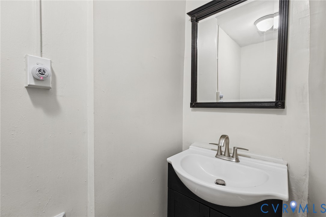 Vanity featuring a dark-finish base cabinet, integrated white porcelain sink, and brushed metal dual-handle faucet, accented by a wall-mounted mirror with a dark frame and a dome-style overhead light fixture