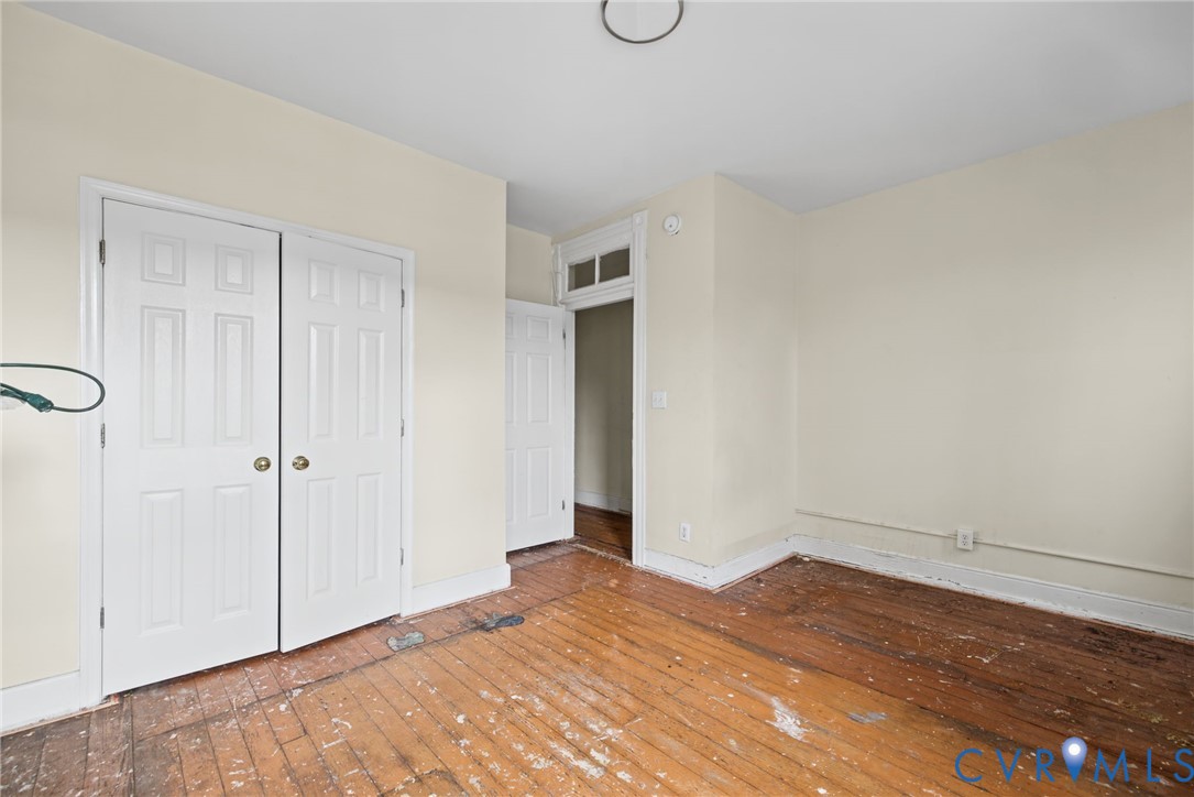 Bedroom 1 - Hardwood flooring, paneled closet doors, and a decorative transom window above the doorway