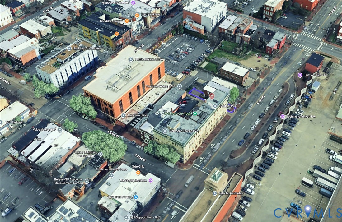 Aerial perspective of a multi-story urban building situated in a dense commercial corridor with direct street frontage and rooftop access