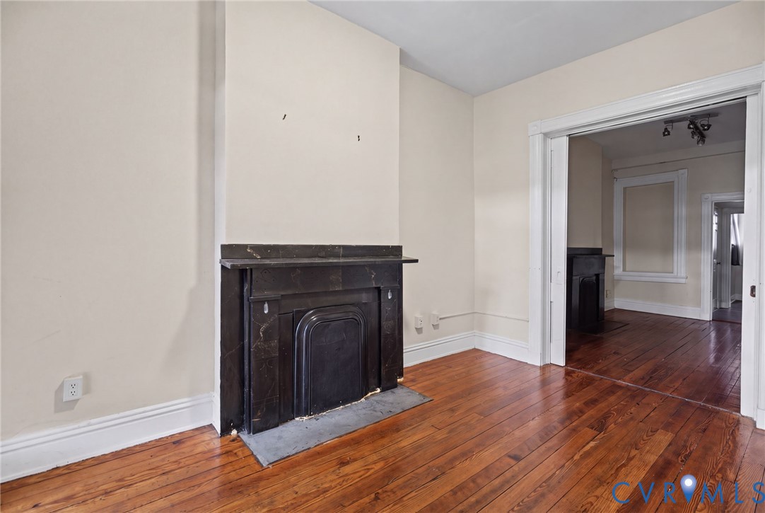 Dark stone fireplace surround with a matching hearth, hardwood flooring, and wide door casing